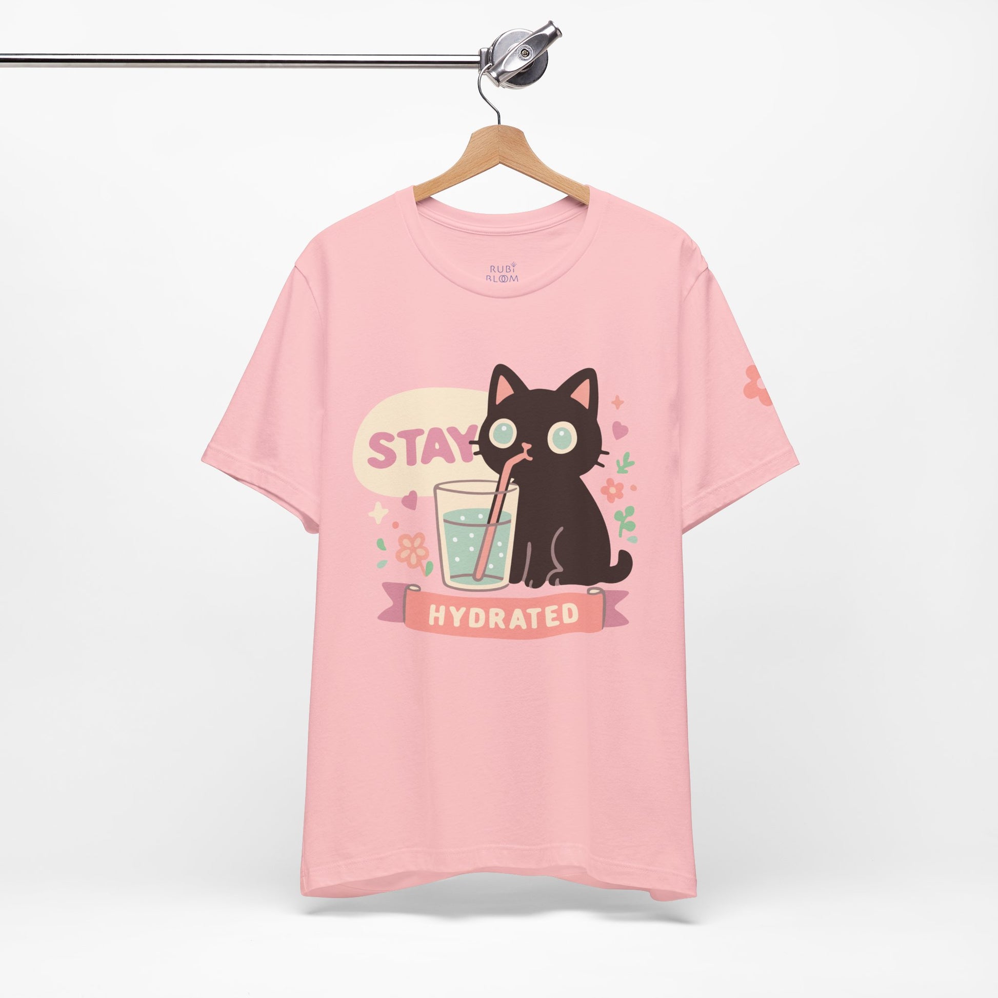 Pink “Stay Hydrated” Ruby Bloom t-shirt — cozy pastel tee with cute cat illustration and hydrating message, ideal for slow mornings and soft style lovers.