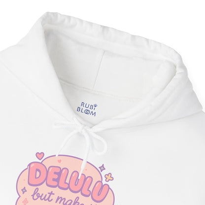 Close-up of pastel print “Delulu but make it aesthetic” on white hoodie — dreamy pink lettering with hearts, sparkles and flowers, RubiBloom cozy aesthetic apparel for soft girls.