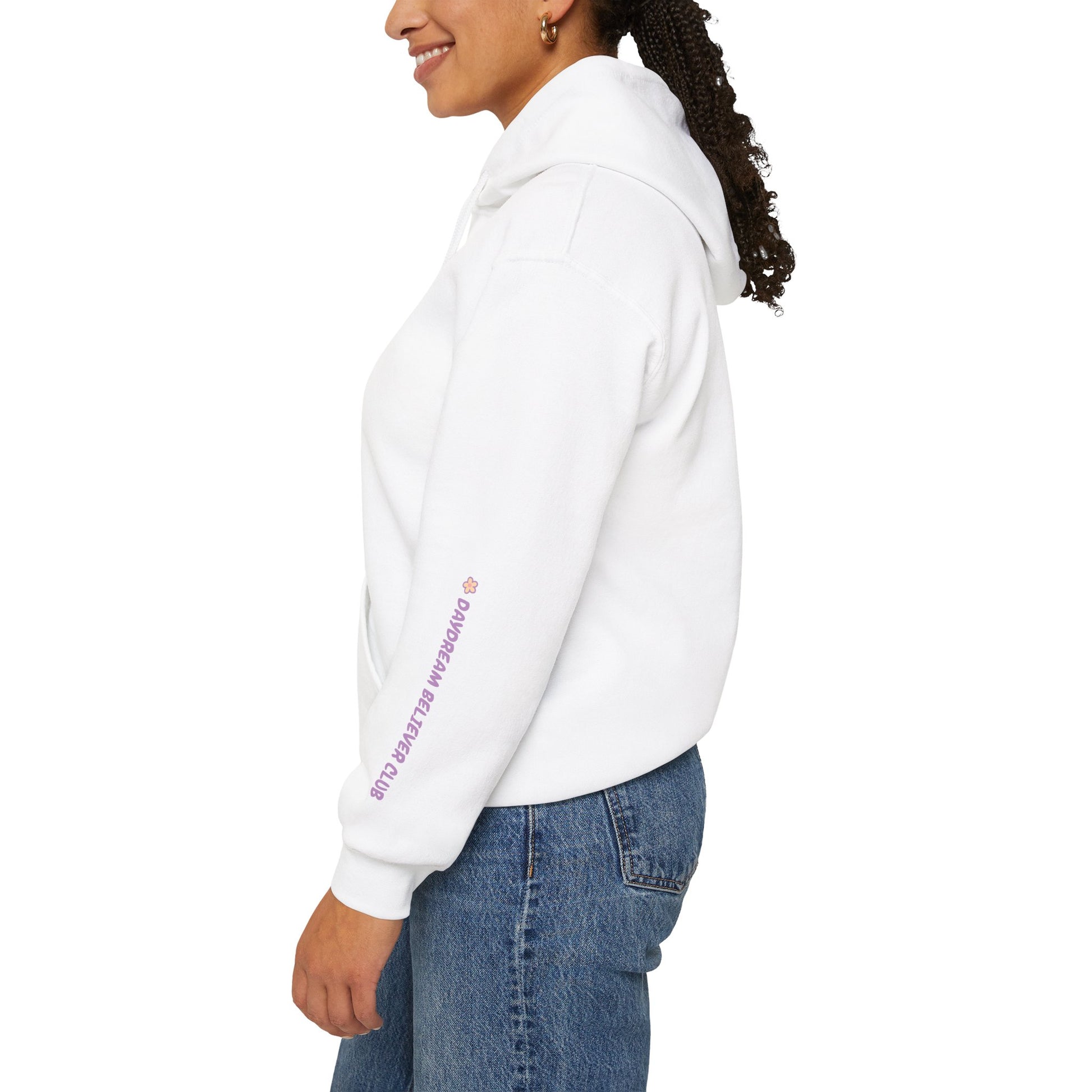 Side view of model wearing RubiBloom white hoodie with pink pastel quote — sleeve embroidery “Daydream Believer Club”, aesthetic cozy fashion piece for slow mornings.