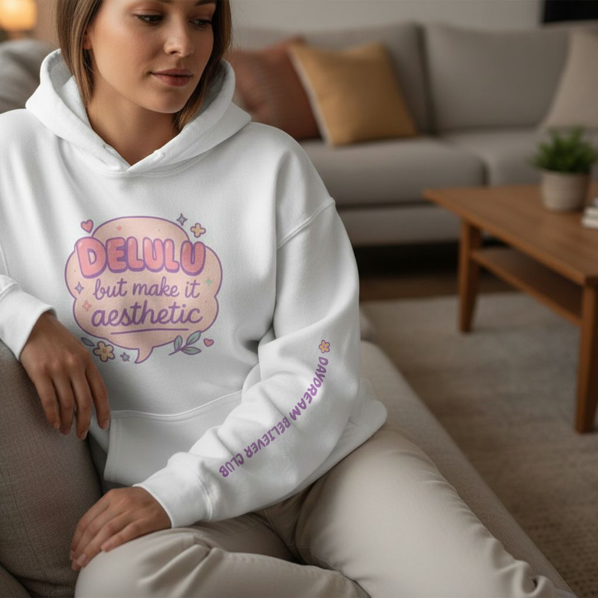 Model wearing white “Delulu but make it aesthetic” hoodie by RubiBloom — soft pastel cozy hoodie with dreamy pink quote bubble and tiny stars, perfect for creative souls and cozy aesthetic lovers.