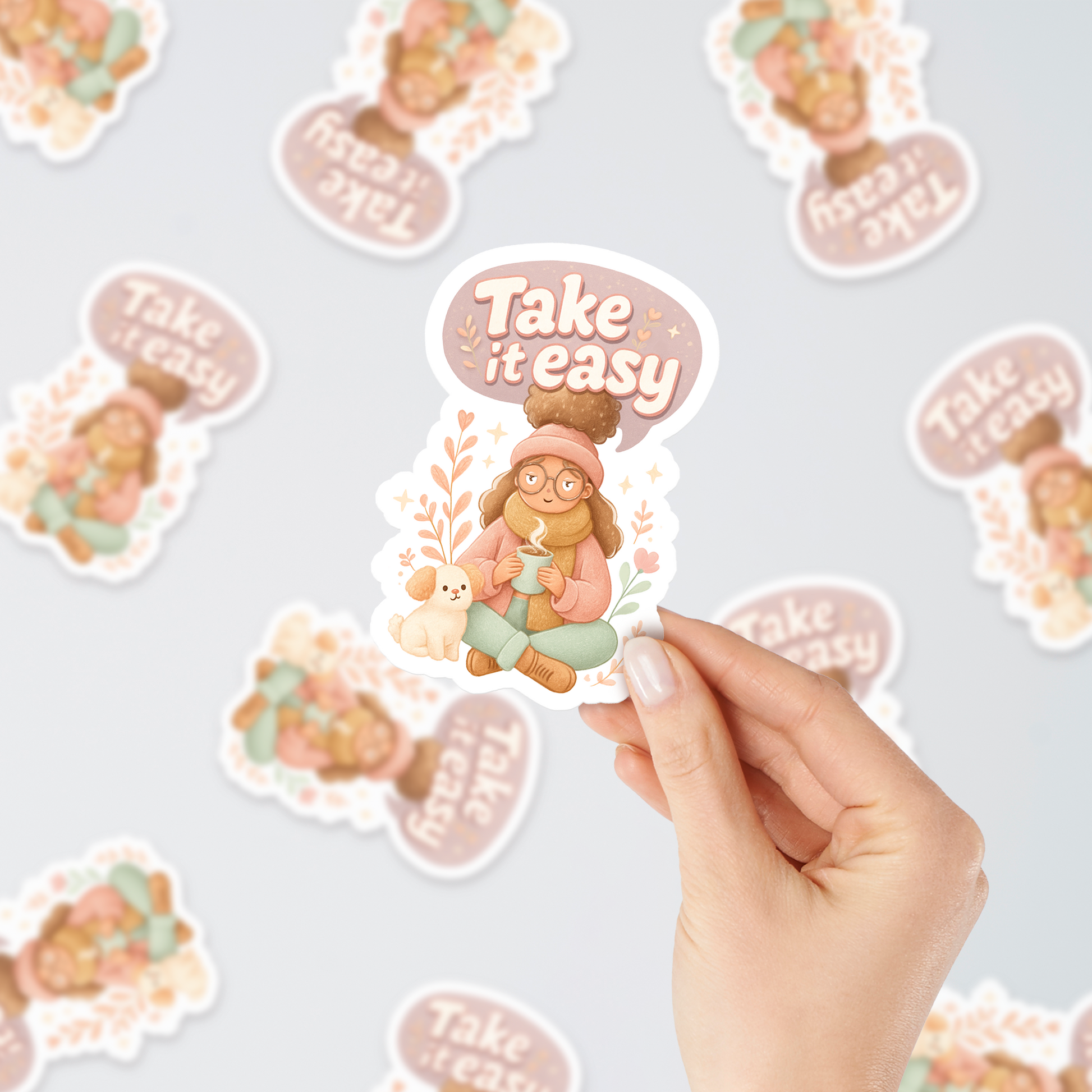 Hand holding “Take It Easy” autumn vinyl sticker with cozy girl and dog design, surrounded by multiple stickers on a light background.