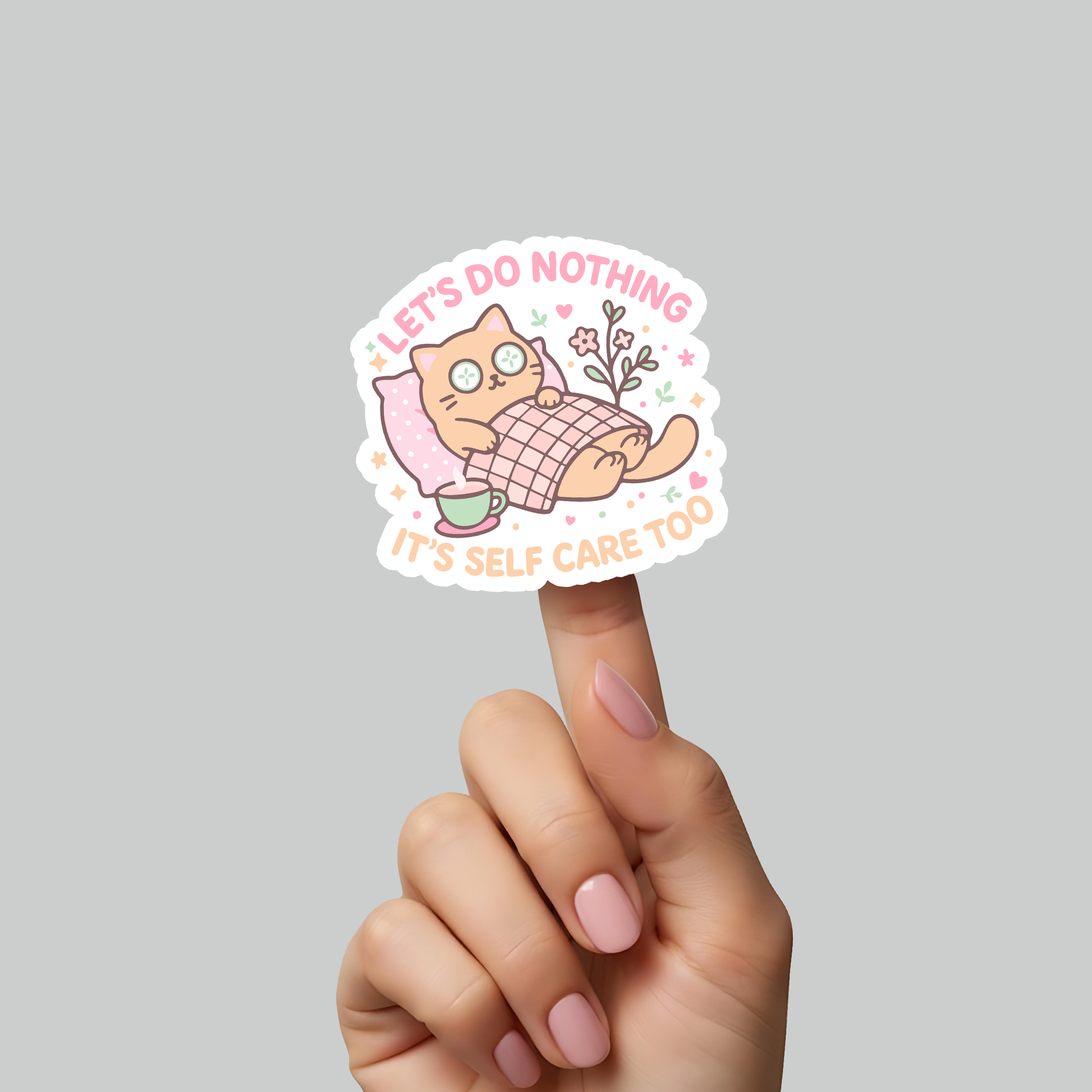 Hand holding RubiBloom “Let’s Do Nothing, It’s Self Care Too” sticker — cute pastel cat illustration under a blanket with coffee cup, cozy kawaii vinyl sticker for self-care lovers and aesthetic journaling.