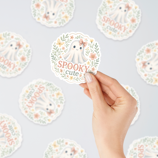 Hand holding Spooky Cute ghost vinyl sticker with floral design – kawaii pastel Halloween decoration for laptops, planners, water bottles, and journals.